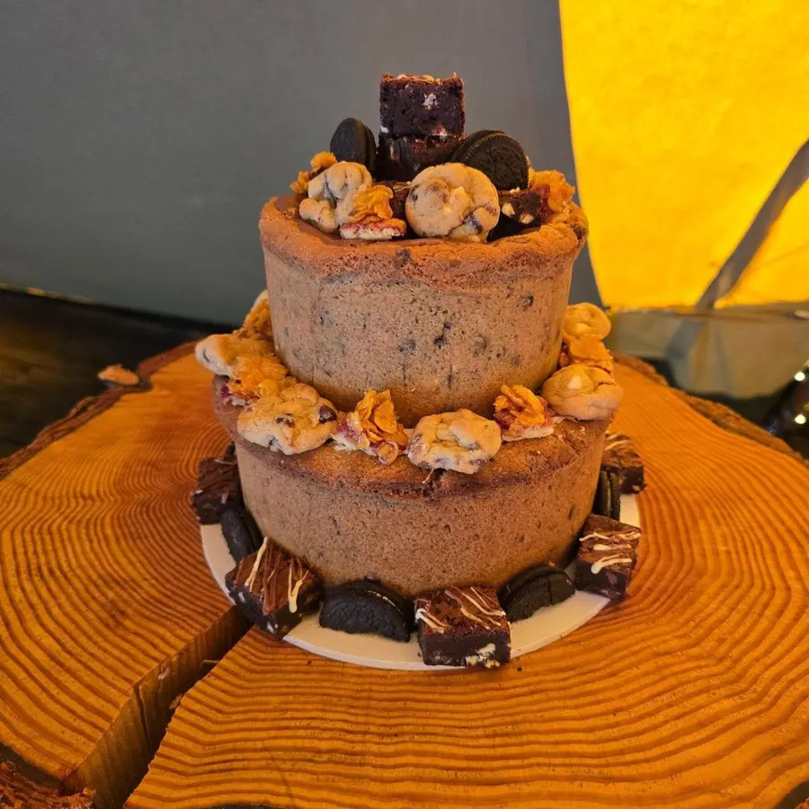 A stacked cookie pie wedding cake topped with brownies and Oreos