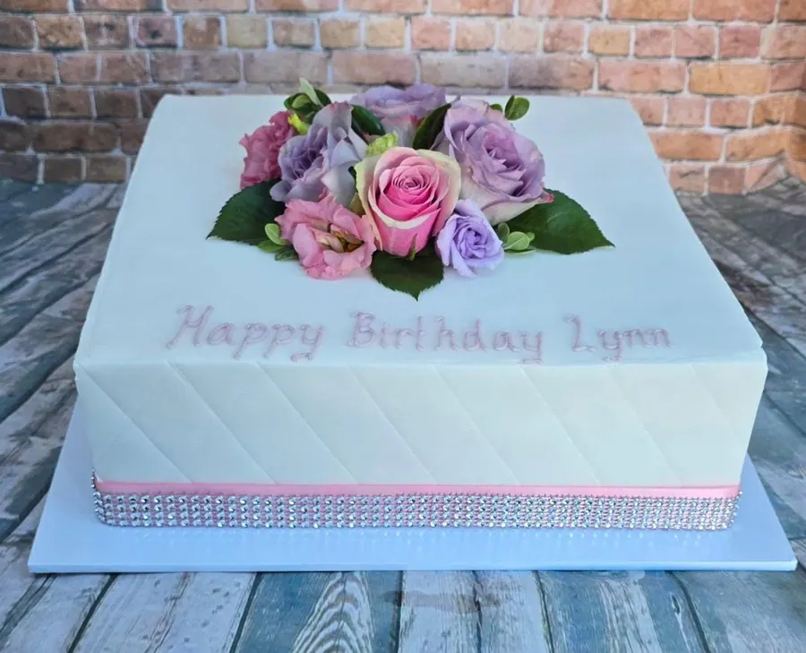 A 12 inch fondant cake with quilted sides and pink and lilac fresh roses