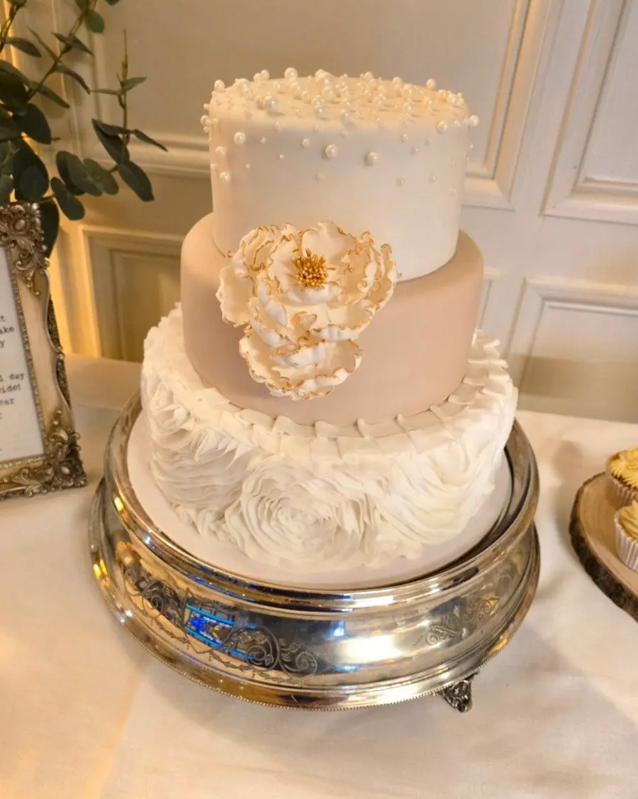 An ivory wedding cake with fondant ruffles and a sugar flower