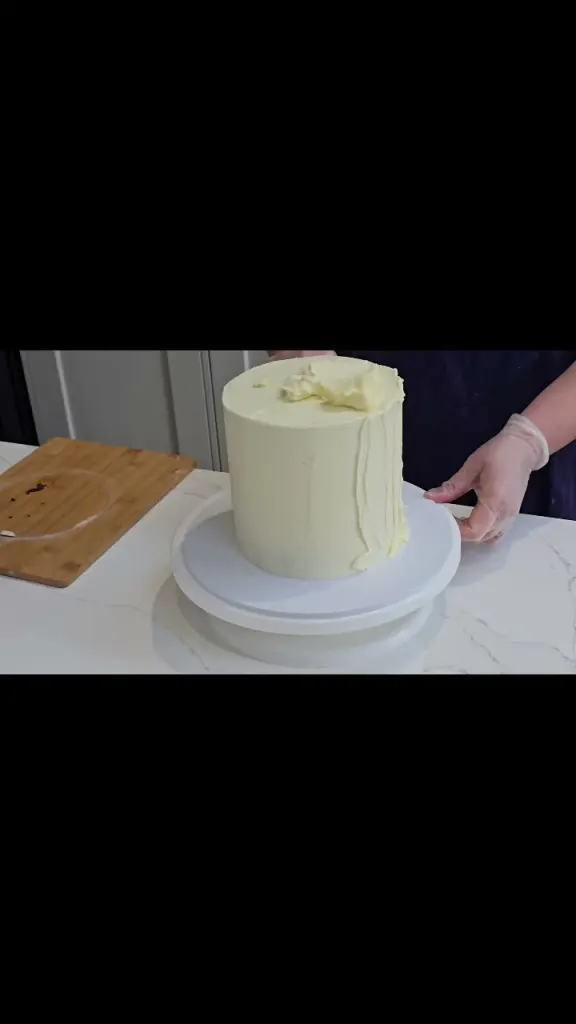 Liz smoothing buttercream on a cake on the turntable